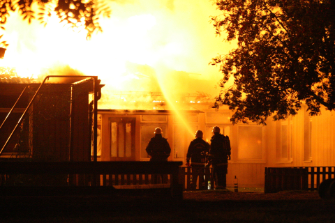 tre brandmän släcker en husbrand