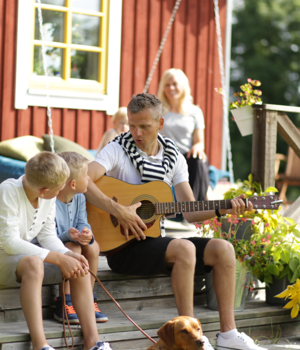 Familj sittandes på terrass utanför hus.