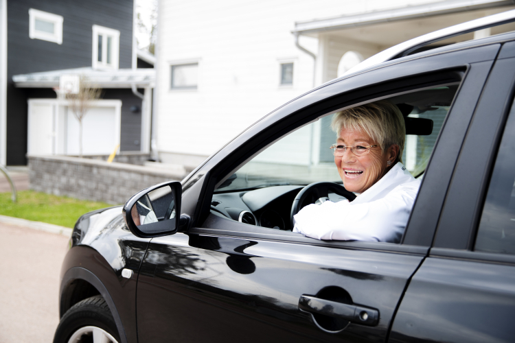 En glad kvinna kör bil i bostadsområde