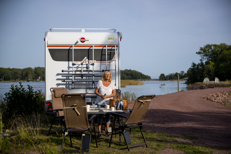 Kvinna dukar bord utomhus bredvid en husbil