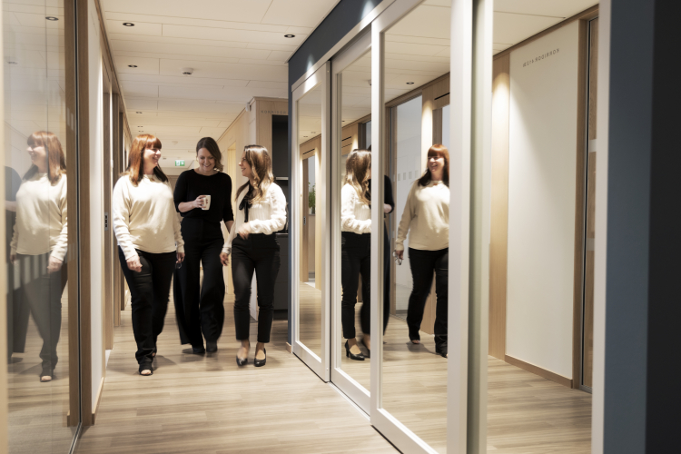 Tre kvinnor kommer gående i en korridor