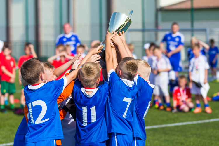 Fotbollslag med blå tröjor som håller i en pokal