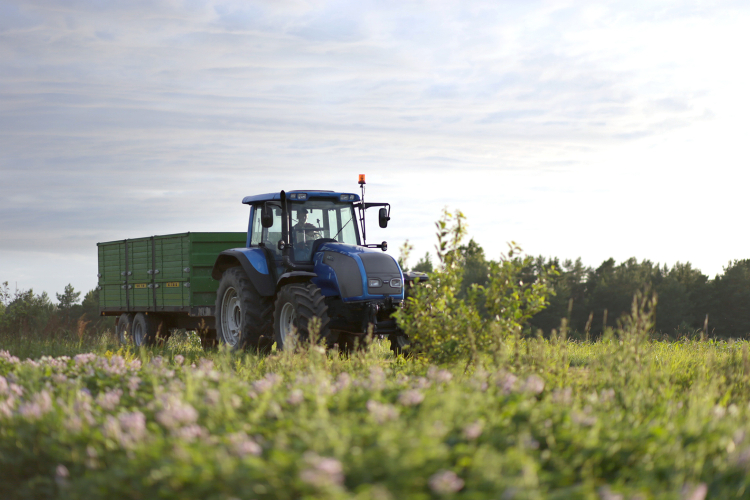 Traktor med släp som kör på åker