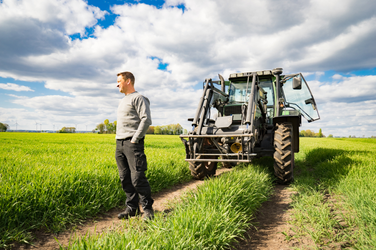 Man står på en åker bredvid sin traktor