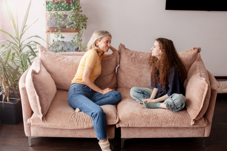 Kvinna och flicka sitter i en rosa soffa