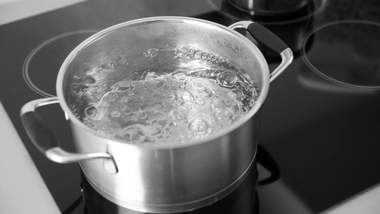 En kastrull med kokande vatten står på spisen. 