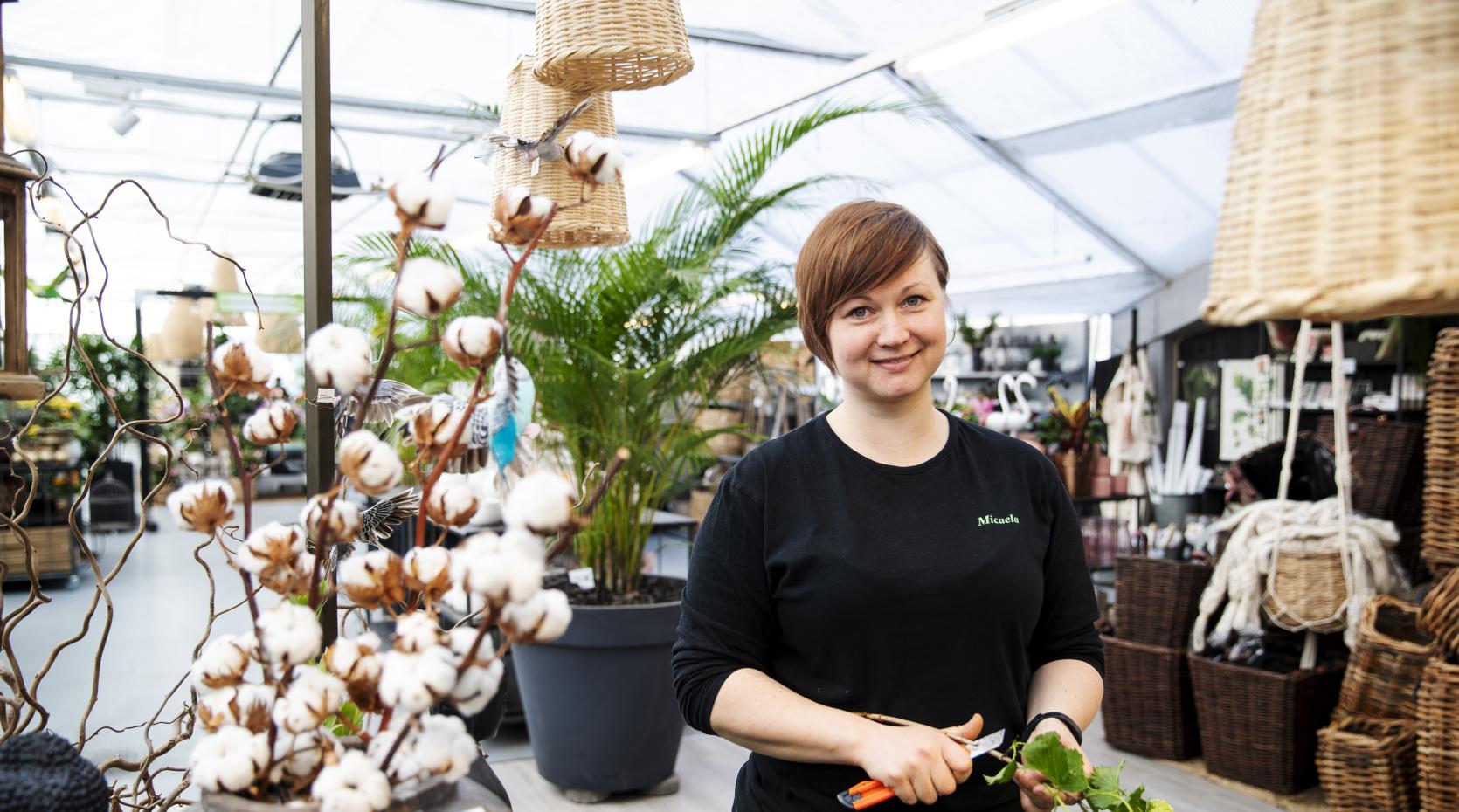 Kvinna står och snittar blommor inomhus