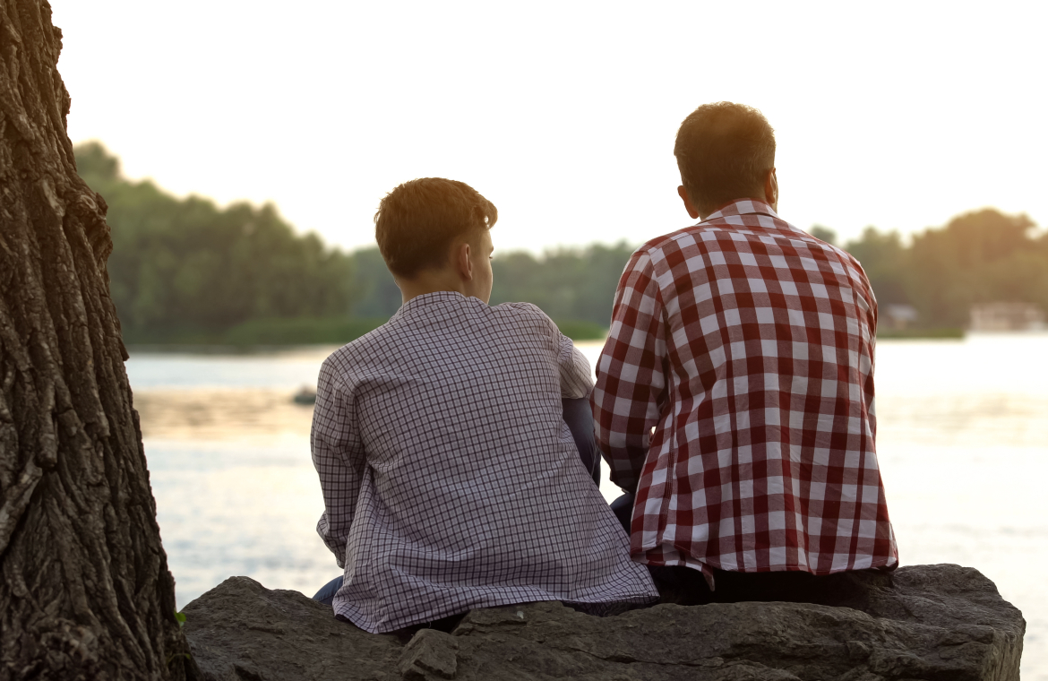 Man sitter med en pojke och tittar ut över vatten